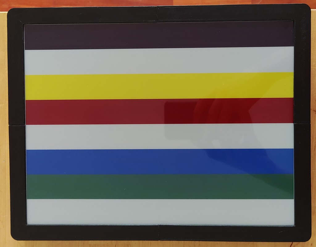 A photo of the frame with 8 colored band displayed. From top to bottom, black, white, yellow, red, white, blue, green, white